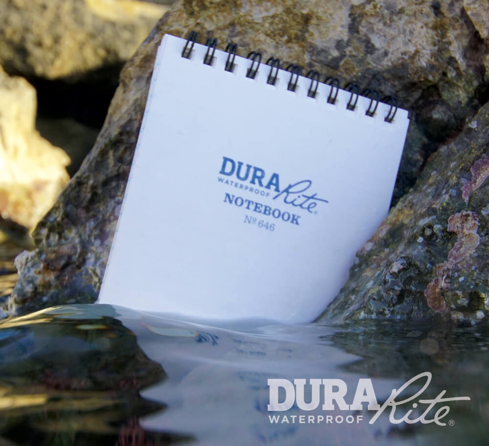DuraRite No 646 notebook in the water against a rock.