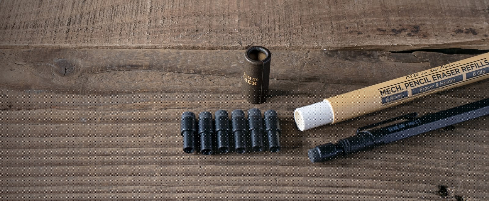 No. 13 Mechaical Pencil Erasers and storage tube laying on wood.