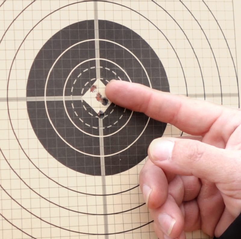 Shooter pointing to bullseye bullet holes.
